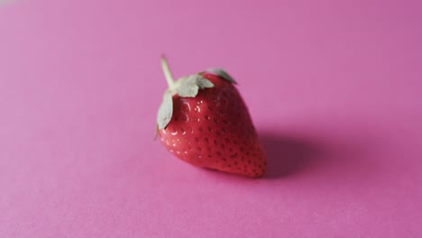Video-of-strawberry-with-copy-space-over-pink-background