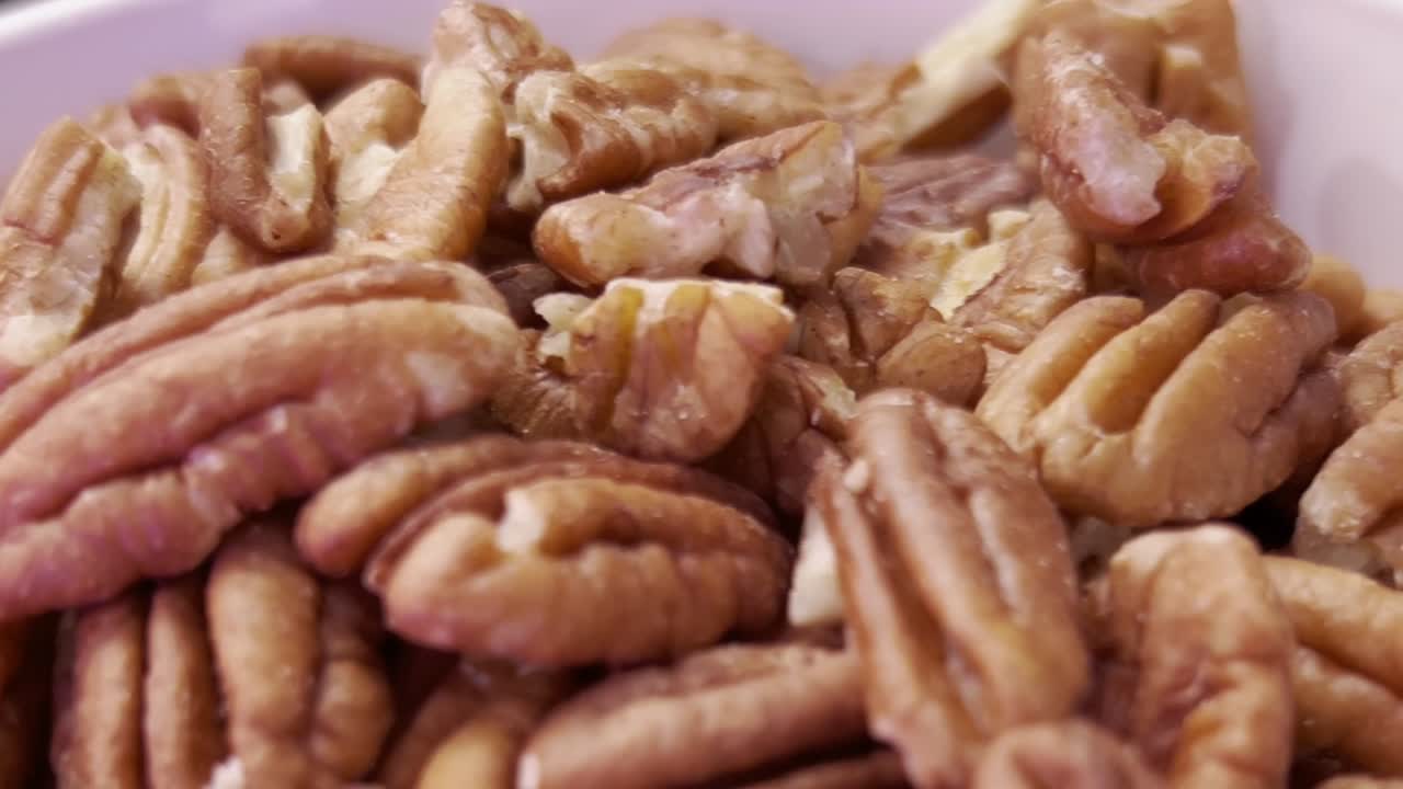Pecan halves forming a textured background, highlighting themes of healthy eating, baking, and the vibrant pecan industry. Ideal for showcasing nutrition and delicious recipes, extreme close up reveal