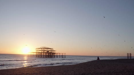 Plano-Amplio-De-La-Silueta-Del-Muelle-Oeste,-Brighton-Al-Atardecer-Con-Pájaros-Volando