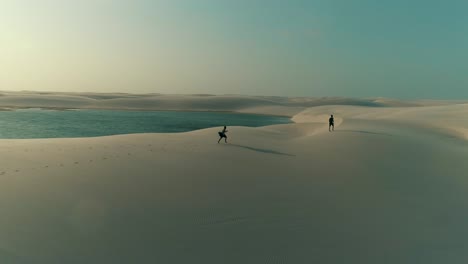 aerial image of men with backpack walking on the dunes in lencois maranhenses national park in brazil