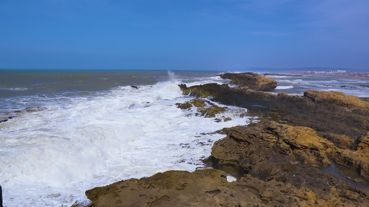Big ocean waves crash against the rocks on the coast. Big sea spray with white foam. Atlantic ocean on a sunny day. Essaouira, Morocco