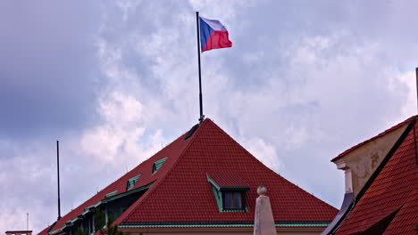 flag of czech republic on flagpole waving in wind on top of tile roof