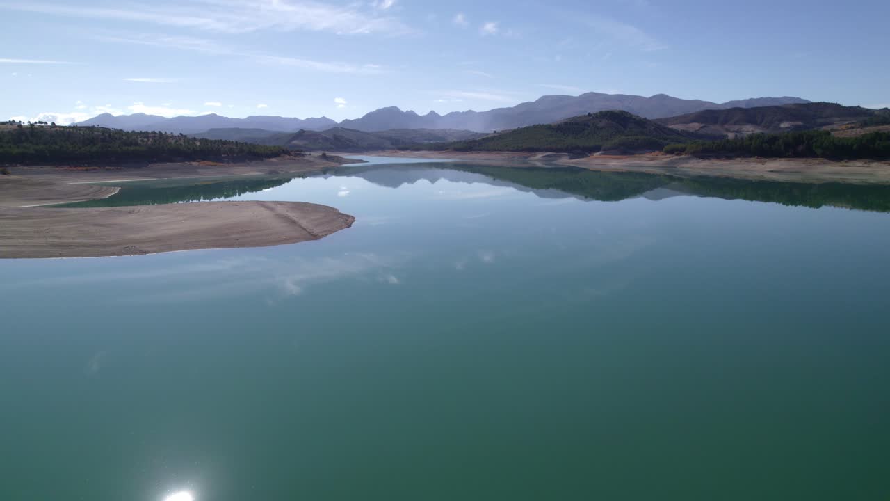 Sky and clouds reflected in the lake waters. Lake with calm waters and the sky reflected in it. Mirror effect. Aerial view of a beautiful lake surrounded by mountains. Granada. Spain