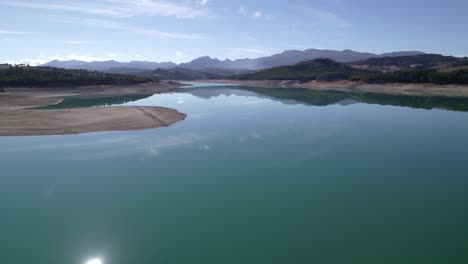 sky and clouds reflected in the lake waters. lake with calm waters and the sky reflected in it. mirror effect. aerial view of a beautiful lake surrounded by mountains. granada. spain