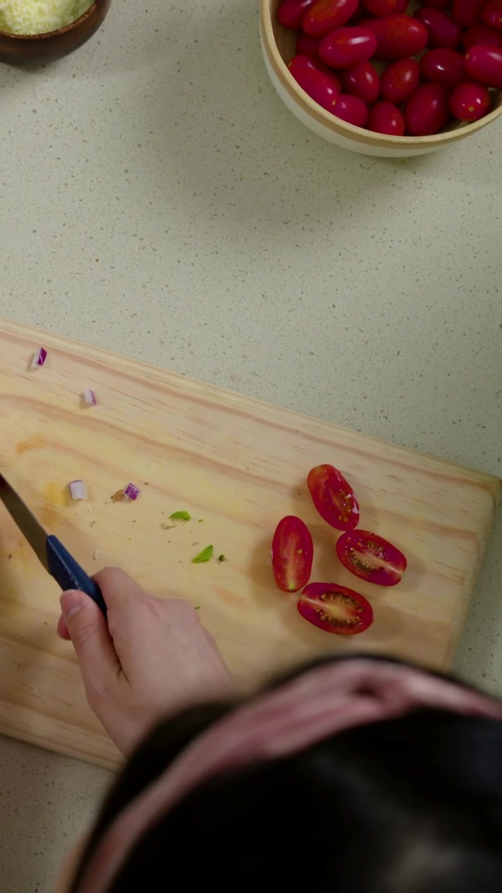 Video verticale: Panoramica su due cuochi che preparano una pasta nel mortaio, tagliano a metà i pomodori sul bancone, con della senape.