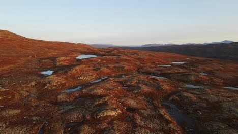 Aufsteigende-Drohnenaufnahmen-Zeigen-Ein-Plateau-Mit-Bergen-Und-Seen-Und-Ein-Tal-In-Der-Ferne