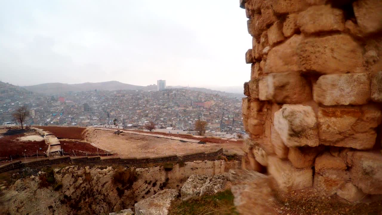 Vista dal muro superstite del Castello di Urfa sul fossato e sulla città moderna, con neve e pioggia.