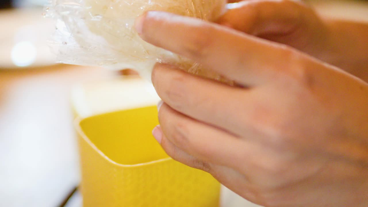 Hands remove sticky rice from woven container, natural lighting, close-up, shallow depth of field