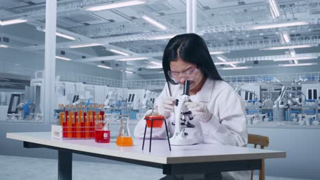 vista lateral de una científica asiática mirando a través de un microscopio en la mesa con un tubo de ensayo luego sonriendo y diciendo wow en el laboratorio, trabajando en el laboratorio analizando muestras bajo el microscopio