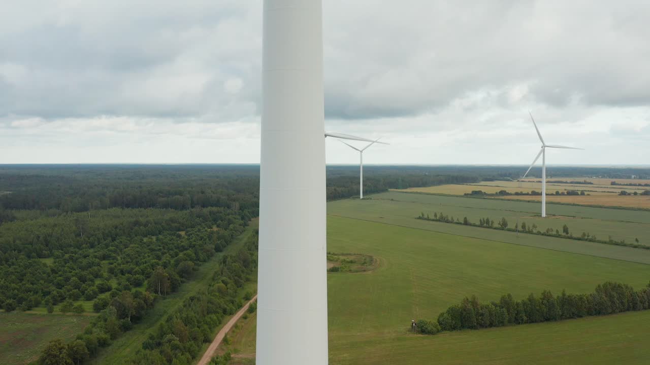 백그라운드에서 풍력 터빈 공원이 있는 회전 풍력 터빈의 상향 공중 근접