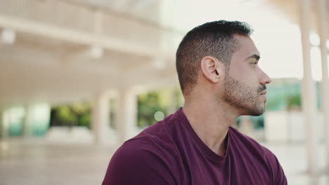 Young-man-looking-around-while-sitting-outdoors.