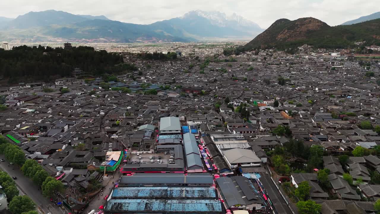 Overhead drone of central square in Lijiang Old Town with streets and rooftops, aerial pullback