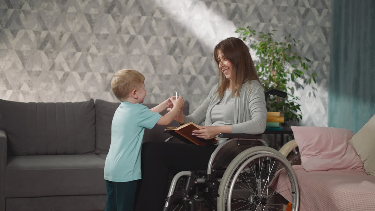 el niño cariñoso trae un vaso de agua mientras la mamá lee