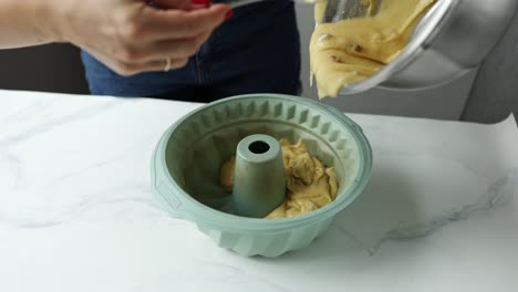 woman pouring batter into a bundt pan