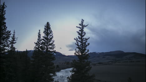 Montañas-De-Campo-De-Lapso-De-Tiempo-Con-Puesta-De-Sol-A-Estrellas-Nocturnas,-Luego-Se-Acerca-Una-Tormenta-De-Nieve-Desde-Río-Arriba