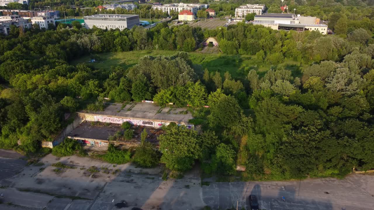 Main concourse and former ticket office with trees surrounding abandoned Edmund Szyc Stadium in Poznan, Poland
