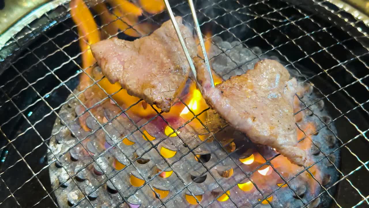 Close-up van kwaliteitsrundvlees dat grilt op een houtskoolbarbecue met intense oranje vlammen.