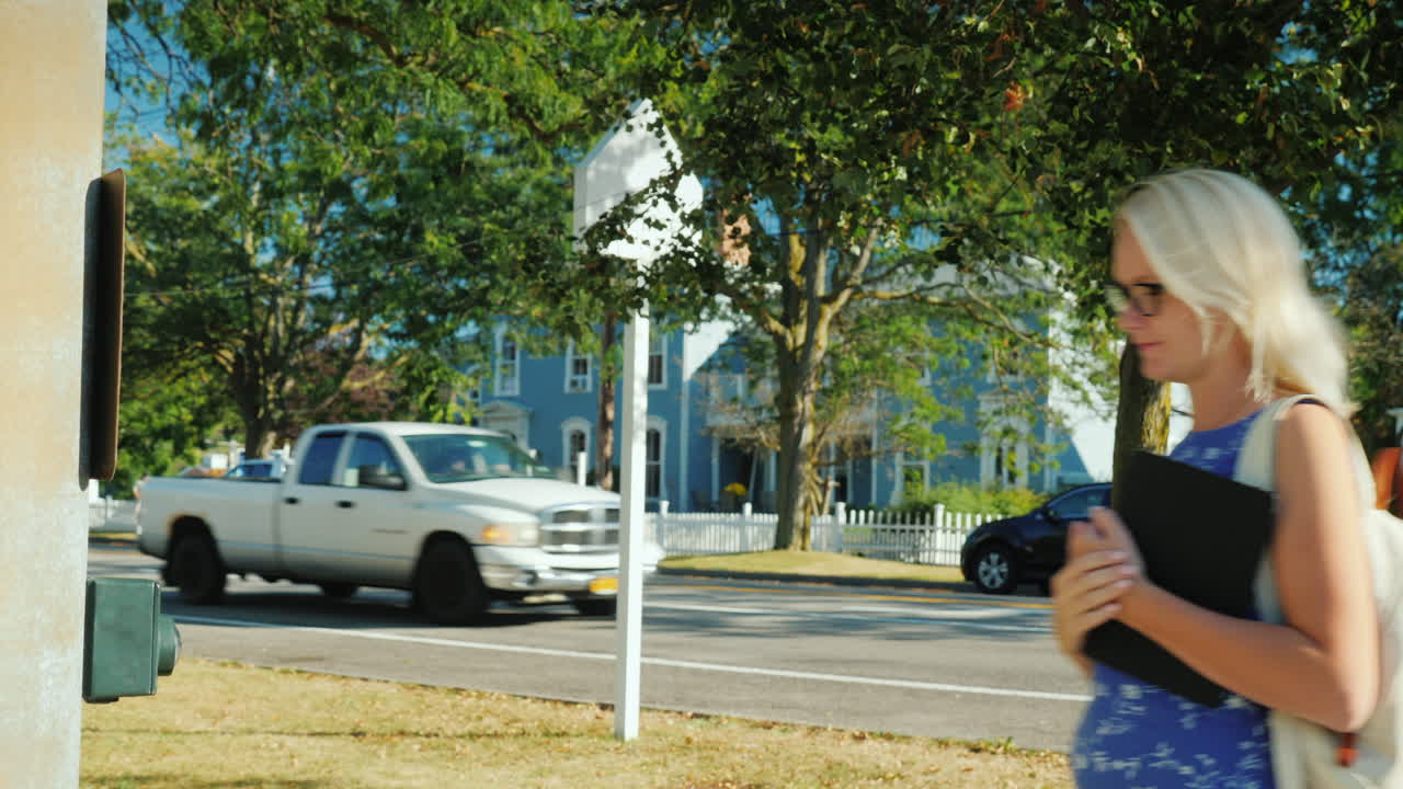 태블릿을 가진 여성이 횡단보도 버튼을 누릅니다.