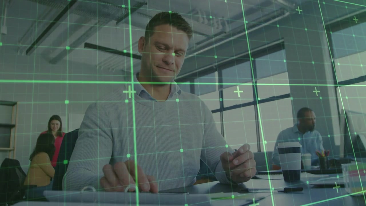 Uomo che sposta il telefono sulla scrivania, lo appoggia e inizia a lavorare, mentre una griglia verde si sposta in sovrapposizione.