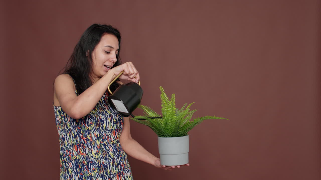 Happy model holding flowerpot and watering green plant