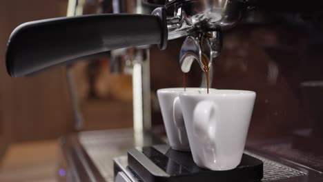 barista fills two espresso cup with freshly brewed italian espresso