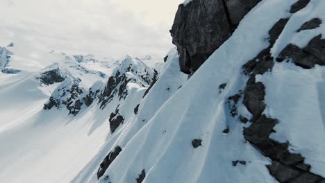 Mountain-ridge-covered-in-snow,-close-up-fpv-drone-flyby