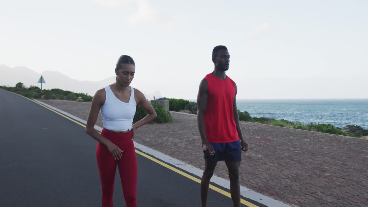 Diverse fit couple exercising running on a country road near mountains