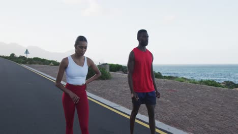 diverse fit couple exercising running on a country road near mountains