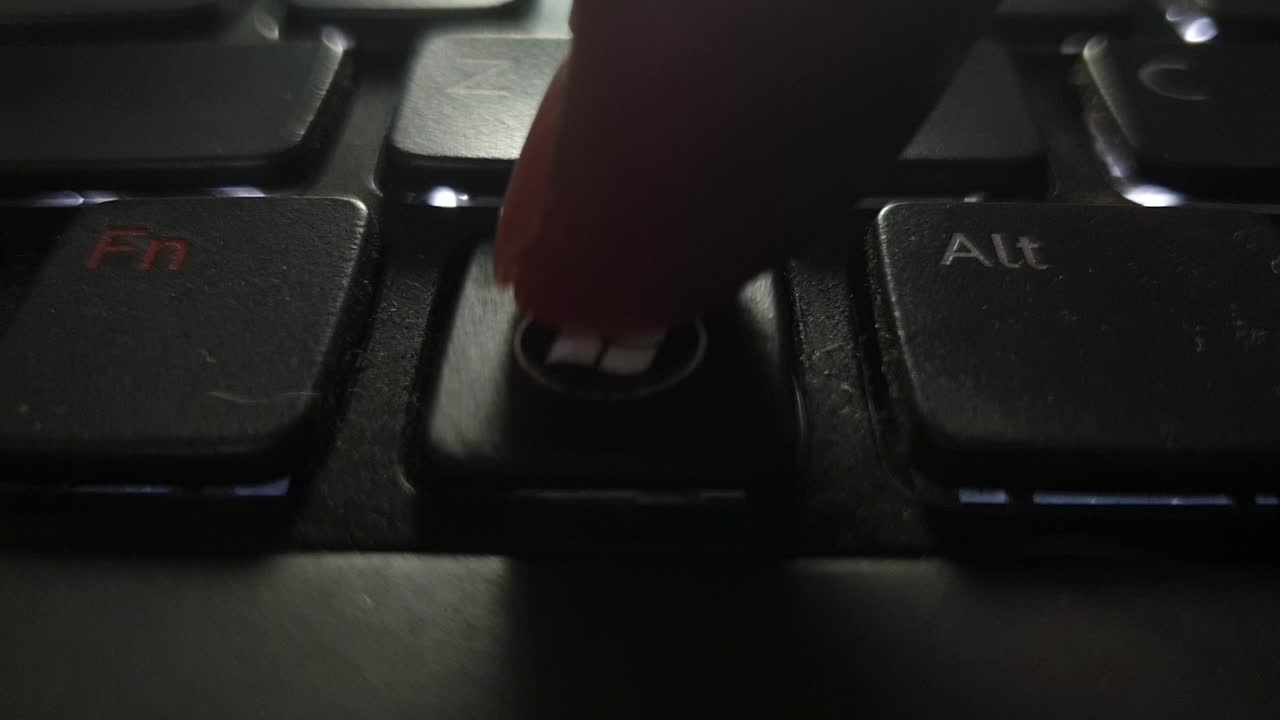 teclado retroiluminado de portátil sucio y roto con suciedad y polvo golpeando la tecla de windows desgastada con el dedo repetidamente