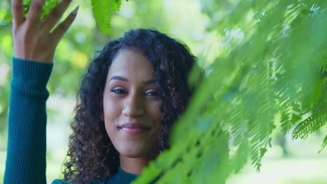 A-young-girl-lifts-tree-branches-to-reveal-her-pretty-face