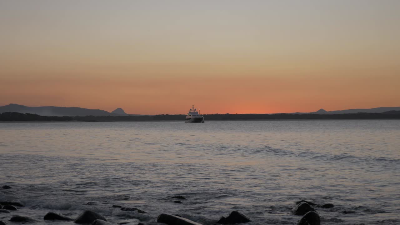 barco a la deriva en las aguas de noosa en el extremo norte de la costa del sol en una puesta de sol - queensland, australia - plano general