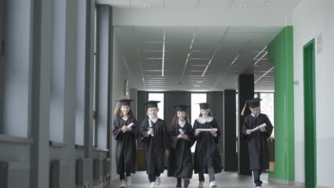 group of happy multiracial preschool students in mortarboard and gown greeting their teacher.