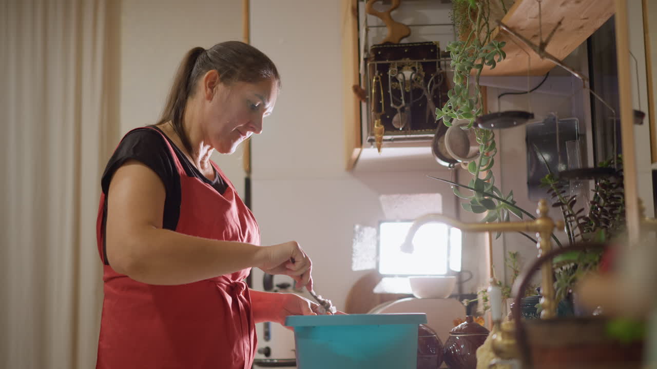 Padeiro caseiro na cozinha misturando massa sob o sol forte da manhã, avental vermelho, tigela azul, plantas em vasos na prateleira, mãos alegres mexendo, xícara medidora e batedor de arame, texturas táteis e cozimento caseiro alegre.