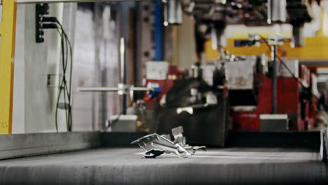 metal car parts on the production line being transferred on a conveyor belt after being molded by an automated hydraulic press in a modern factory