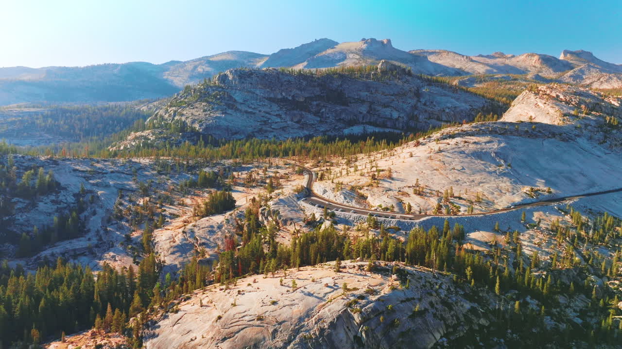 Magnificent white rocks with some pine trees growing on. Road with cars around the mountain. Sunny scenery of Yosemite National Park, California, USA.