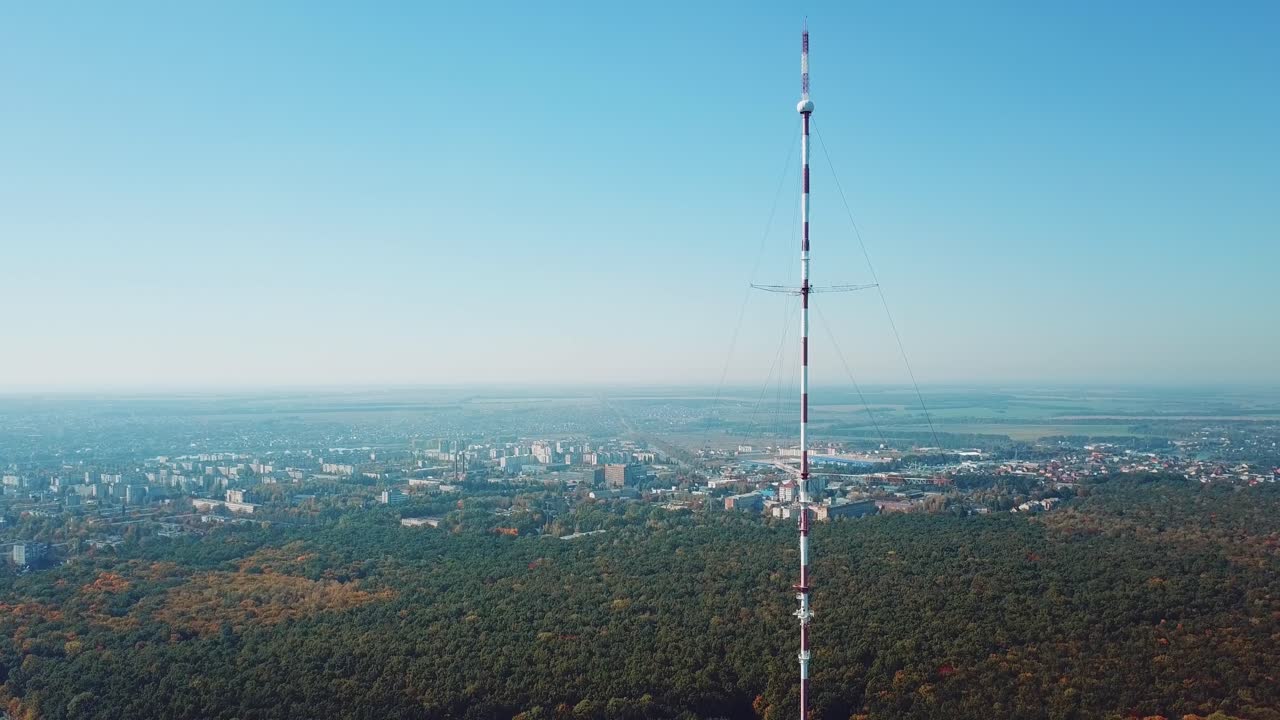 one telecommunication tower is located near the city in the background of the forest. Camera motion back