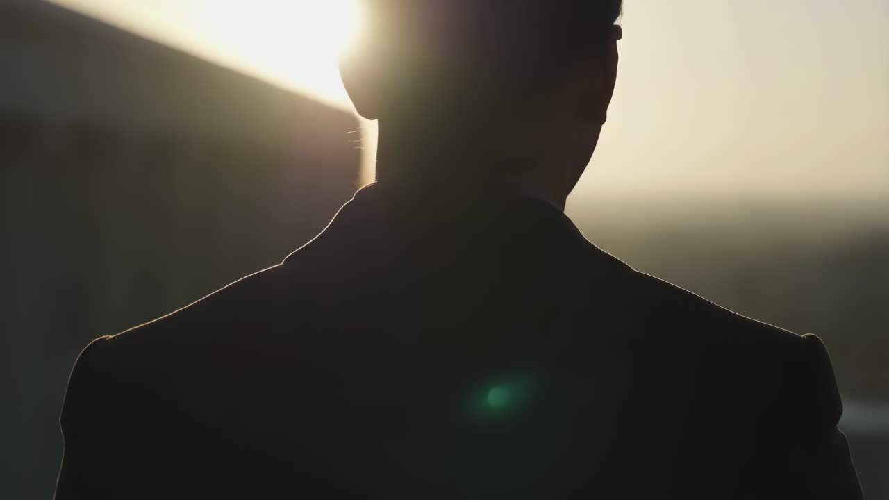 Silhouette of a man in a suit looking towards a bright sky