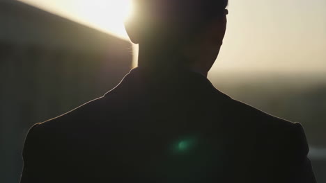 silhouette of a man in a suit looking towards a bright sky