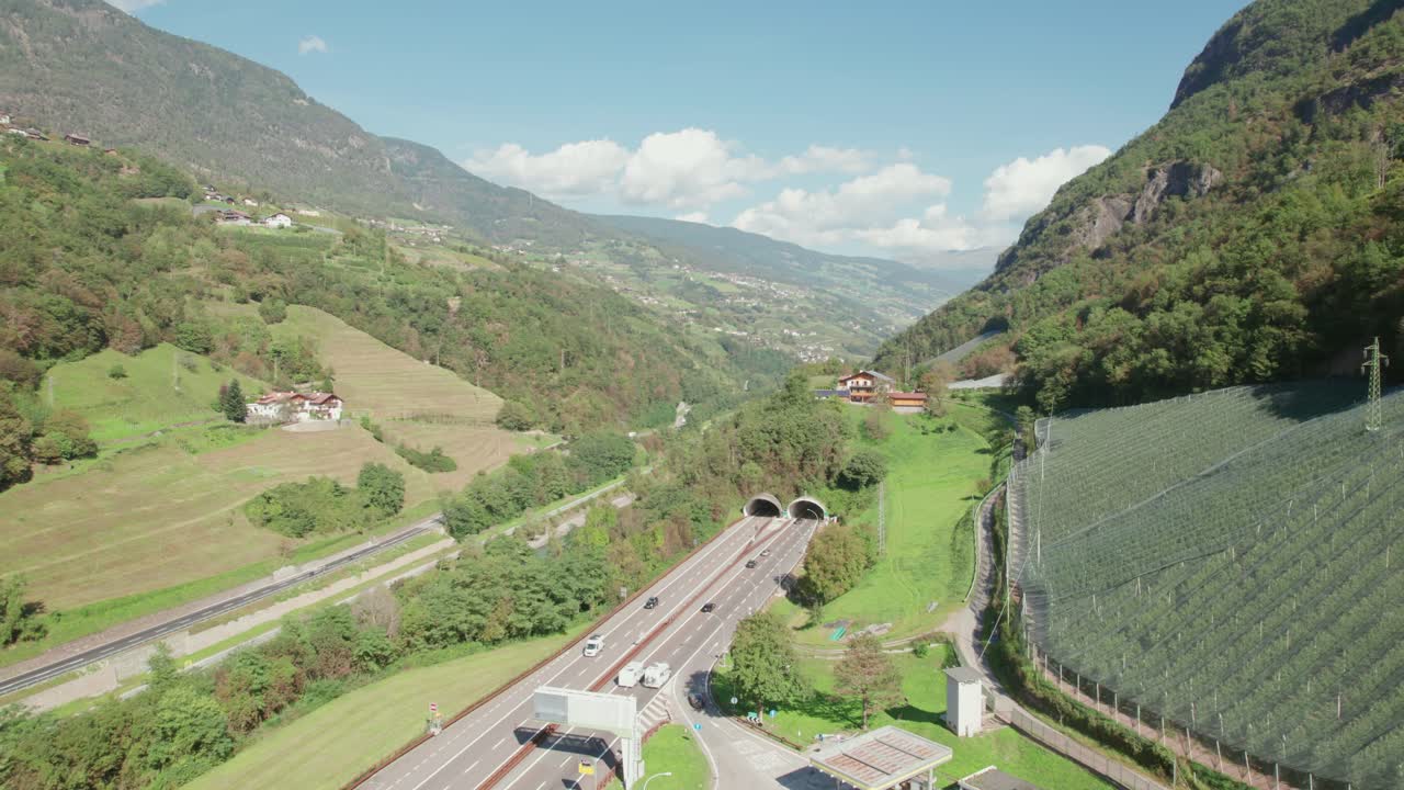 carretera que atraviesa la montaña junto al río, coches que van al túnel, que suben vista de avión no tripulado, tiempo soleado