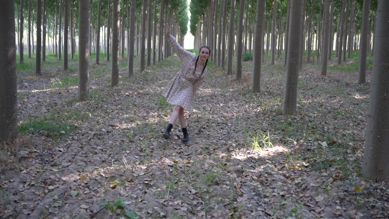 Seorang wanita muda berjalan-jalan di jalur hutan yang tenang dan indah, dikelilingi oleh alam.