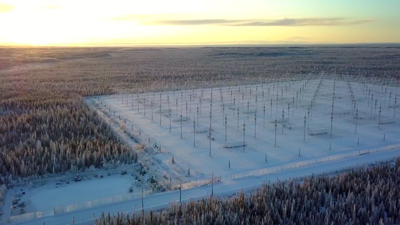 aéreo, pan, disparo de drone, del conjunto de antenas haarp, en medio de los bosques de alaska, al atardecer, en una tarde soleada de invierno, en gakona, alaska, estados unidos