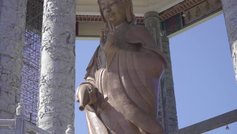 the statue of the goddess of mercy, kuan yin, at the entrance of kek lok si temple in penang malaysia on sunny day - tilt down shot