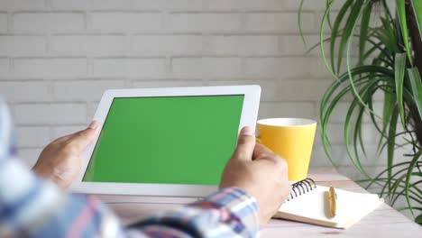 vista trasera de un joven demandando una tableta digital con pantalla verde