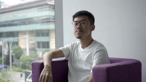 asian man sitting down on a chair and being passed a piece of paper for an interview getting ready to speak