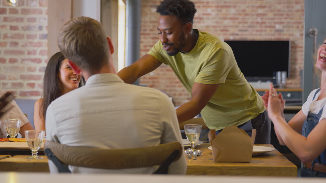 grupo multicultural de amigos disfrutando de bebidas y comida para llevar en casa juntos