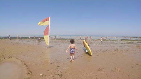 following shot of happy little girl toddler running across the beach