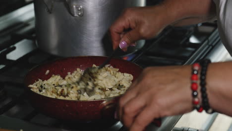 revolviendo la cebolla y las hierbas en una sartén en la cocina con una cuchara