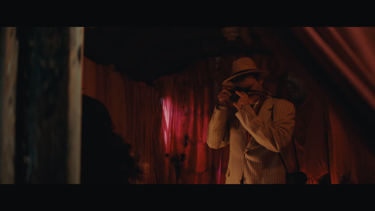 A man in hat takes a photo of the gypsy lady inside the circus cart