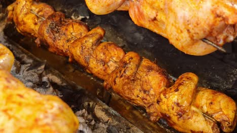 rotisserie chickens roasting over charcoal