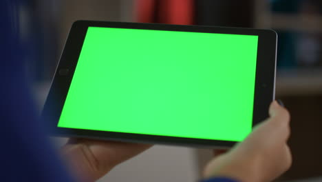 African-american-woman-holding-tablet-digital-device-green-screen-in-home-office